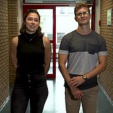Zwei Studierende stehen in einem Korridor vor einer Tür